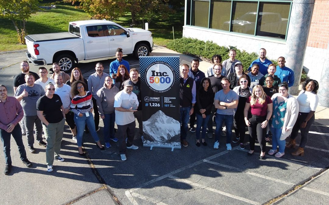 Here is a picture, taken from a drone, that shows a group of MA solar installers. They are standing in a parking lot and they are holding an Inc. 5000 sign given to Summit Energy.