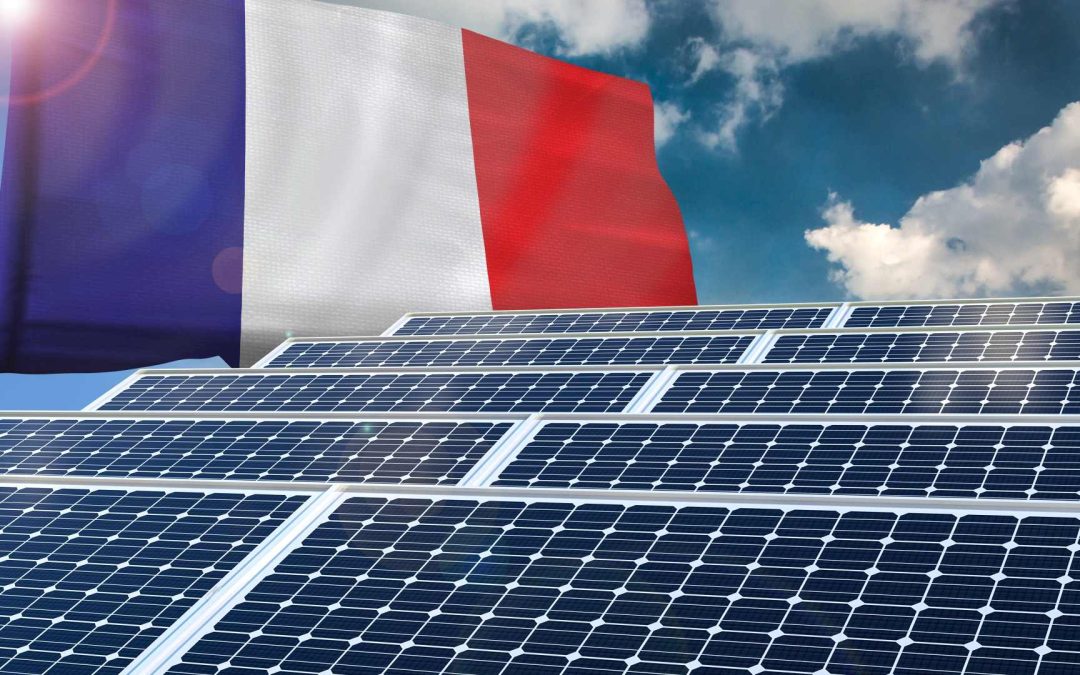 Here is an image of four solar panels laid under the sun and a blue sky with clouds. Above the solar panel, it’s the flag of France.