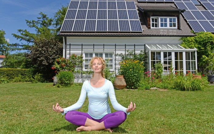 Yoga instructor in front of House with solar panels.
