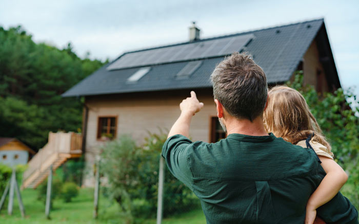 Rare of dad showing solar panel installed on the roof of the house to his kid.